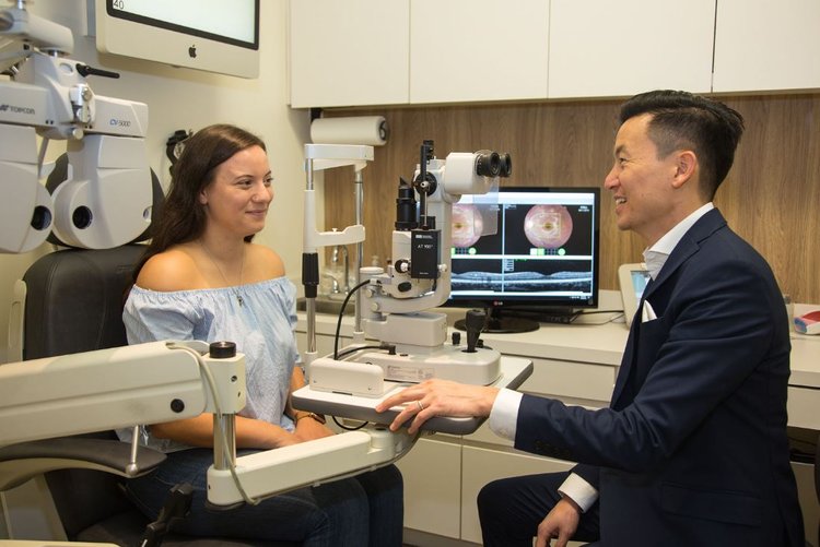 Eye Exam An optometrist performing a comprehensive eye exam on a patient using advanced diagnostic equipment in Oakville.